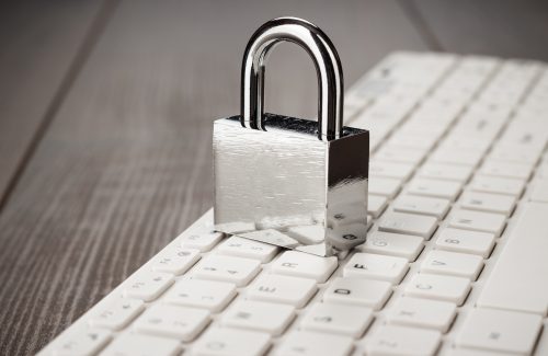 padlock and white computer keyboard on the wooden office table. privacy protection, encrypted connection concept